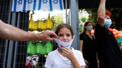 A parent adjusts their child's face mask as pupils return to school in Tel Aviv. Reuters