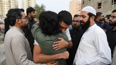 People comfort Imam Rafay Siddiqui, front, son of crew member Muhammad Arif Siddiqui, during a funeral prayer in absentia in Karachi. EPA