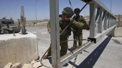 An Israeli soldier opens a gate at a checkpoint between the West Bank city of Hebron and a commercial crossing point into Israel on August 7, 2008.
