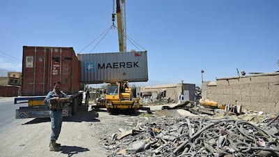 Policemen stand guard as workers unload a container at a junkyard near the Bagram Air Base. AFP
