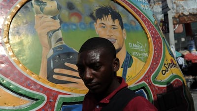 A man walks past by a bus painted with the face of Brazilian football player Neymar in Port-au-Prince. Popularly these buses are called TapTap and are painted with faces of football players, international personalities and other striking designs. Hector Retamal / AFP