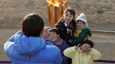 A family takes a selfie with the Olympic flame. EPA