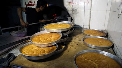 A baker takes dishes of rawani dessert out of a wood-fired oven during the holy month of Ramadan in Sanaa, Yemen April 16, 2021. Reuters