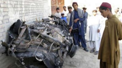 Tribesmen look at a vehicle destroyed by a missile attack in Mir Ali on the outskirts of Miranshah, near the Afghan border, November 1, 2008.
