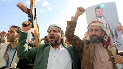 Houthis brandish their weapons and hold up portraits of leader Abdul Malik Al Houthi during a protest in Yemen on January 12. AFP