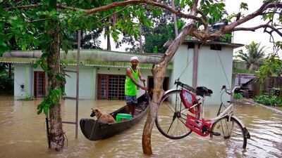 A man passes a cycle tied to tree to stop it being washed away in Kerala's Alappuzha district. AP Photo