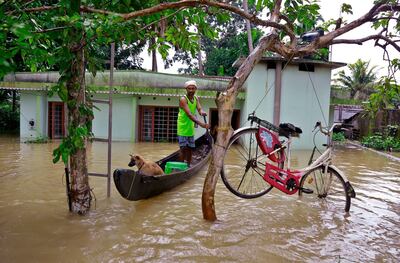 A man passes a cycle tied to tree to stop it being washed away in Kerala's Alappuzha district. AP Photo