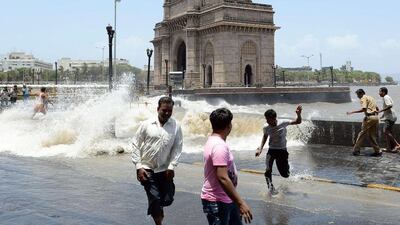 Pedestrians run as seas swollen by monsoon rains send waves on to the road near the Gateway of India in Mumbai on June 13, 2014. Indranil Mukhurjee / AFP