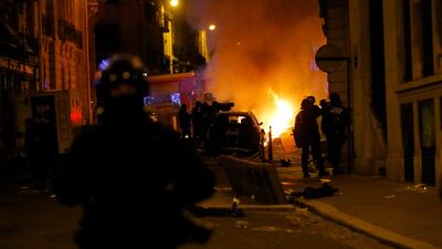 French police officers watch a car burning near the Champs-Elysee. AP
