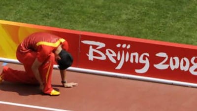 China's Xiang Liu clutches his ankle during the warm up prior to the first round of the men's 110m hurdles.
