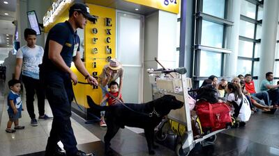 An airport security officer and his dog unit inspect passengers' baggage at Manila's international airport. Noel Celis / AFP