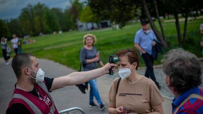 A security member measures the temperature of visitor as people attend a concert of Chinaski music band in Prague, Czech Republic. EPA