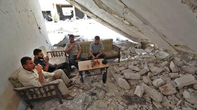 Syrian men from the town of Khan Sheikhun in the south of the northwestern Idlib province, sit for tea in a destroyed home on August 3, 2019. AFP