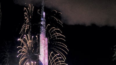 Smoke billows from the Address Downtown Hotel, after it caught on fire hours earlier, past fireworks, near the Burj Khalifa, the world's tallest tower in Dubai, on January 1, 2016. At least 16 people were injured when a huge fire ripped through a luxury 63-storey hotel, the Address Downtown, where crowds were gathering to watch New Year's Eve celebrations. The cause of the blaze was not immediately known but the building was safely evacuated. AFP PHOTO