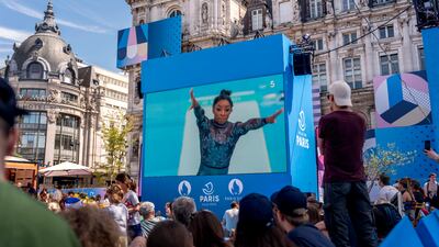 Spectators watch from a fan zone set up at the Hotel de Ville, as Simone Biles, of the US, performs on the vault during a women's artistic gymnastics qualification round at the 2024 Summer Olympics. AP
