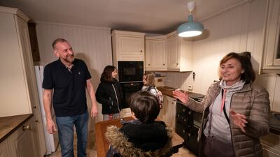 Mick Swinhoe shows Iryna Starkova and her grandchildren around the kitchen of their new home.