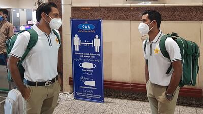Pakistani cricketers Sarfaraz Ahmed, left, and Asad Shafiq wearing facemasks arrive at the Allama Iqbal International airport in Lahore before their departure to England on June 28. AFP