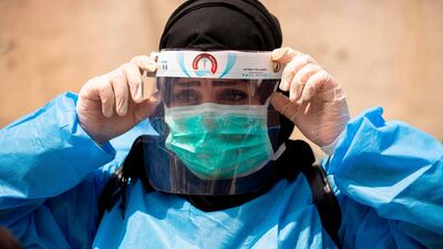 A medical worker dressed in PPE prepares to take swabs from subjects being tested for Covid-19 coronavirus disease Iraq's southern Basra. AFP