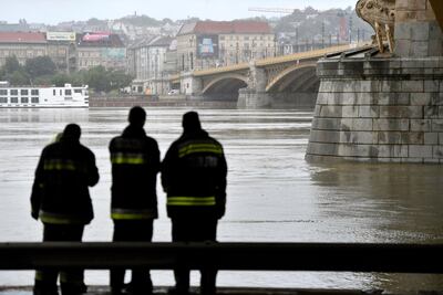 Firemen stand at Margit Bridge, where the wreck of a sightseeing boat was found on the Danube River in downtown Budapest, Hungary. MTI via AP
