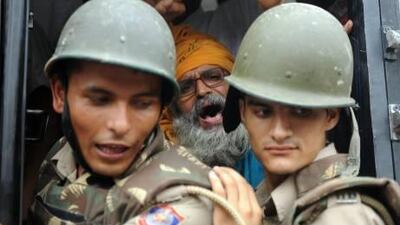 Indian security personnel stand in front of an arrested supporter of Indian social activist Anna Hazare as he shouts slogans from a police bus in New Delhi.