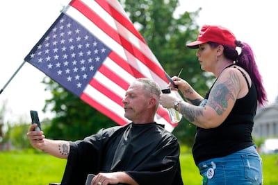 Trump supporter Laina Moore of Elma, Washington gives a haircut to Darren Culbertson of Yelm, Washington on the lawn of the State Capitol as people protest a stay-at-home order which prohibits barbers and stylists from taking clients, Olympia, Washington, May 9. About 1,500 people rallied against Governor Jay Inslee’s stay-at-home order. Jason Redmond / AFP