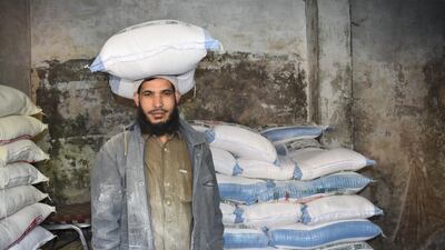 Abdullah Shah, a shop worker, loads bags into a vehicle for customers. Pakistan's government is rationing the distribution of flour amid rising prices.