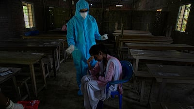 A reluctant student gestures hesitantly before a health worker takes her nasal swab sample after classes started at a college in Jhargaon village, outskirts of Gauhati, India. AP Photo