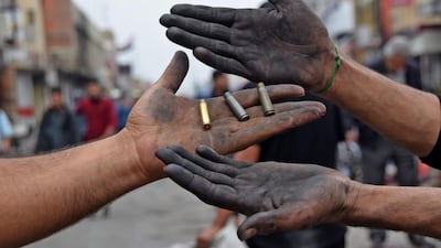 Men holding up spent bullet casings found at a protest site in Habboubi Square in Iraq's southern city of Nasiriyah in Dhi Qar province. AFP