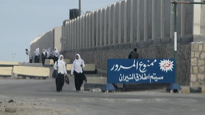 Egyptian schoolgirls pass by a sign in Arabic reading "no passing, will open the fire’’ in Arish in the Sinai peninsula on November 17, 2014. AFP