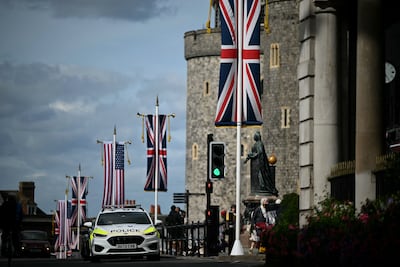 A police car drives past flags flying outside Windsor Castle. AFP