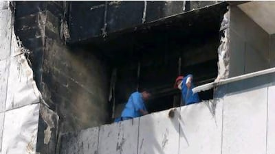Workers cleaning the balcony of one of the damaged flat in Saif Belhasa building in Tecom area in Dubai.
