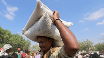 A man carries sacks of grain he received from an ICRC aid distribution centre in Bajil, Yemen. Reuters. File.