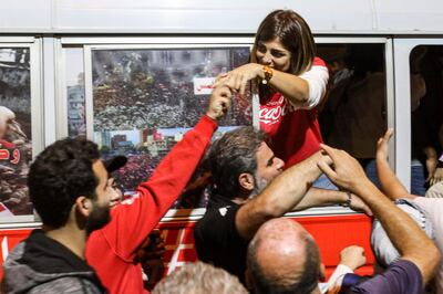 A Lebanese anti-government protester shakes hands with another supporter from a "revolution" bus on a cross-country trip from the north to the south of the country. AFP