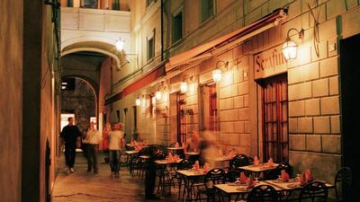 Tourists walking past Restaurant at nigh in Italy.