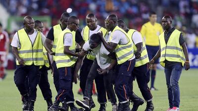 Security personnel take an Equatorial Guinea supporter who stormed the pitch during the African Cup of Nations semifinal soccer match between host Equatorial Guinea and Ghana in Malabo, Equatorial Guinea, Thursday, Feb. 5, 2015. With riot police protecting the players from incensed rival fans and using tear gas to disperse troublemakers in the crowd, Ghana advanced to the African Cup of Nations final with a 3-0 win over host Equatorial Guinea on Thursday. (AP Photo/Sunday Alamba)
