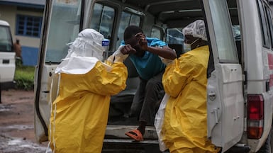 Medical staff wearing personal protective equipment help a patient out of an ambulance at a hospital in Rwampara, Democratic Republic of Congo. EPA
