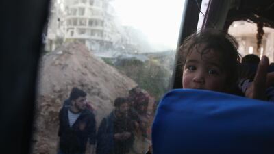 A convoy transporting Syrian civilians and rebel fighters drives past destroyed buildings in Arbin in Eastern Ghouta as they are evacuated from the opposition enclave to the village of Qalaat al-Madiq, some 45 kilometres northwest of the central city of Hama, on March 25, 2018. Abdulmonam Eassa / AFP