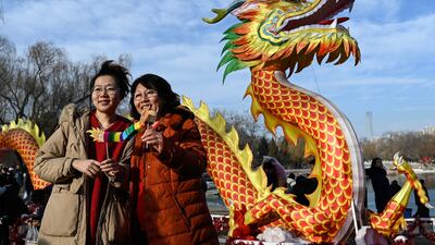 Women pose for a photograph next to a dragon figure at the Longtan Park Fair on the second day of the Lunar New Year of the Dragon in Beijing. AFP
