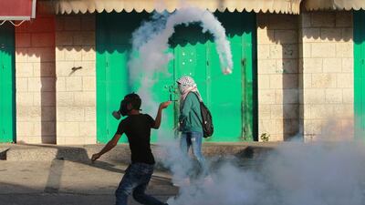 A Palestinian protester uses a slingshot to throw back a tear gas canister towards Israeli security forces during clashes on October 15, 2015 in the West Bank city of Bethlehem. Musa Al Shaer/AFP Photo