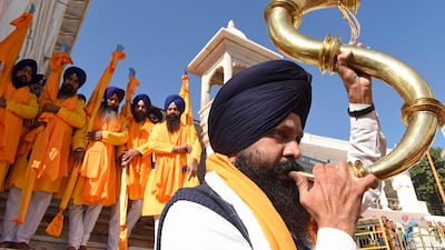 A devotee plays a musical instrument as Sikh holy men known as 'Panj Pyare' hold religious flags during a 'Nagar Kirtan', holy procession ahead of the 551st birth anniversary of Sikhism founder Sri Guru Nanak Dev, at the Golden Temple in Amritsar. AFP