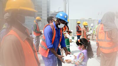Young volunteer hands out food and snacks to construction workers, part of the initiative by the Supreme Council of Motherhood and Childhood, in Abu Dhabi. Khushnum Bhandari / The National