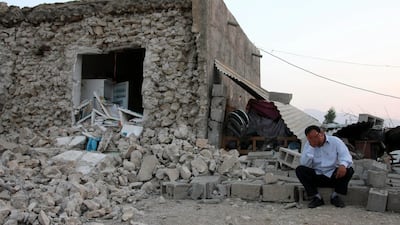 An Iranian man reacts as he sits among ruins of a building. AP Photo / Mohammad Fatemi