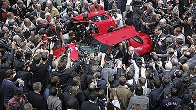 Dieter Zetsche, chief executive officer of Daimler, centre right, and Lewis Hamilton, Formula One's world champion, centre left, are swamped by photographers and reporters at the Frankfurt unveiling of the Mercedes SLS AMG.