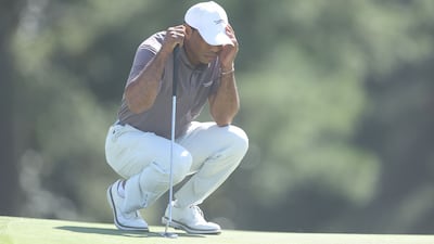 Tiger Woods shields his face from sand on the 18th green at Augusta. AFP