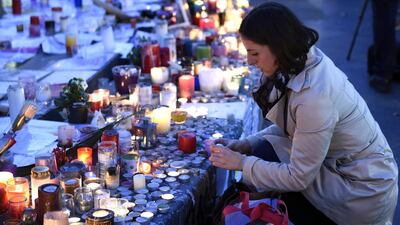 A woman lights a candle at a makeshift memorial at the Place de la Republique in Paris. Eric Feferberg / AFP