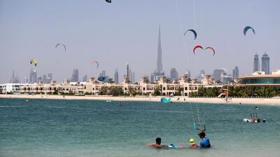 Kite surfers fill the sky as people go to the beach on a hot day in Dubai.