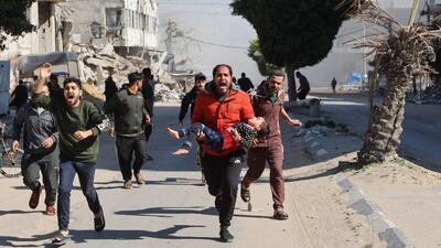 A Palestinian man carrying an injured girl rushes away from an Israeli strike in Gaza City on Sunday. AFP