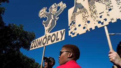 People carry a placard with a parody of one of the Gupta brothers during a demonstration march in Cape Town. Rodger Bosch / AFP
