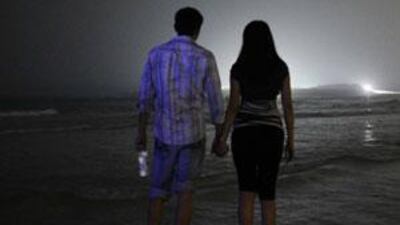 A couple walk on the public beach at night, near the Jumeirah Beach Hotel.