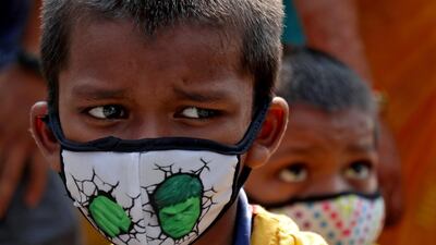 Children wearing protective masks wait to enter the Lokmanya Tilak Terminus railway station in Mumbai, India. Reuters